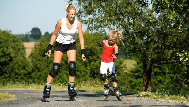 A young mother roller skating with her daughter