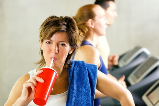 Mature woman has a refreshing softdrink after a workout on the treadmill