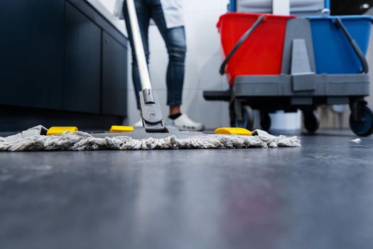 Low shot of cleaning lady mopping the floor in restroom beside her trolley