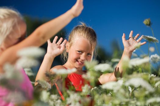 Two young children (sisters) playing in a field of yarrow