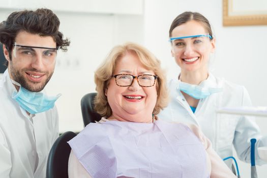 Dentists and patient in surgery looking at camera smiling