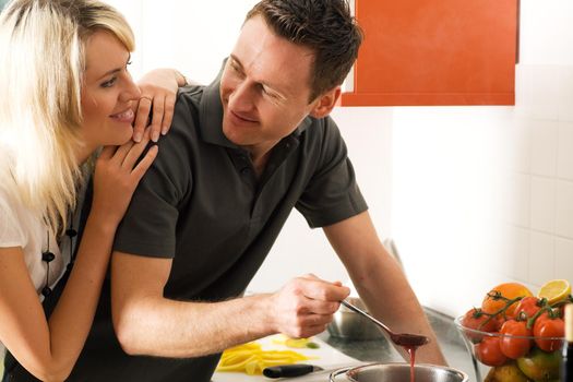 Young couple cooking (in this case: strawberry sauce for dessert)