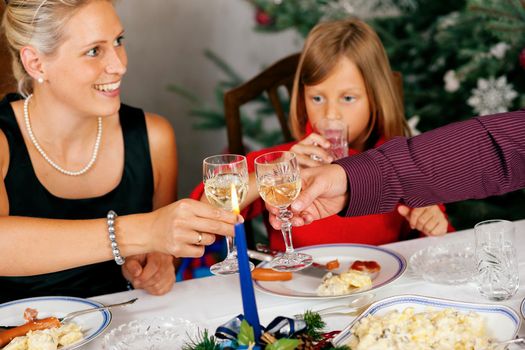 Family eating a traditional Christmas Dinner in front of the Christmas tree