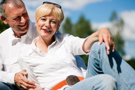 Visibly happy mature or senior couple outdoors arm in arm deeply in love