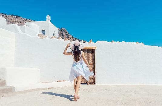 Woman approaching a greek house with a white wall