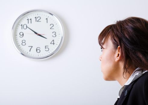 Female office worker looking at a clock on the wall