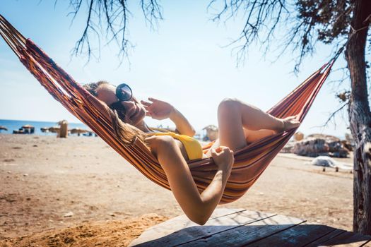 Woman lying in hammock close to the beach enjoying the sun