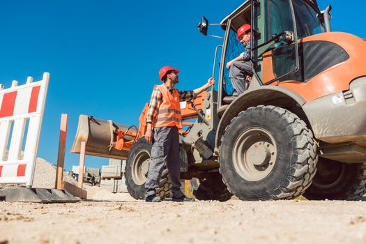 Construction worker starting road works on site with machine