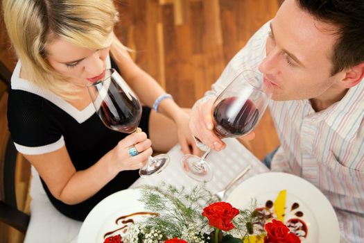 Young couple romantic dinner: both drinking red wine and having desert