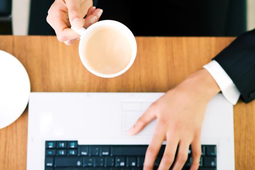 A woman (just hands) at her workplace having a double espresso (focus on hand and cup)