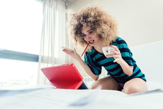 Woman student on her bed learning for exam in panic and despair