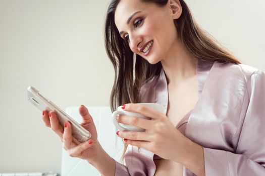 Woman checking her phone in the morning for messages on bed