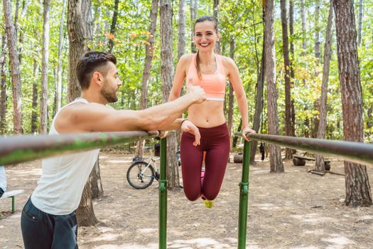 Fit and beautiful woman exercising on parallel bar with her boyfriend