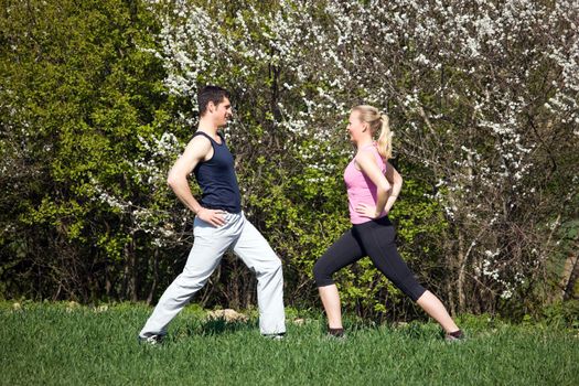 Young sportive couple doing stretching exercises in a spring setting