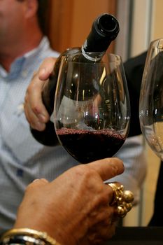 salvador, bahia / brazil - december 12, 2006: person is seen pouring wine into glass during tasting of the drink in the city of Salvador.