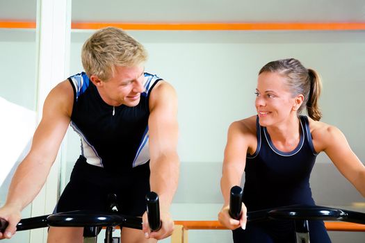 Couple using bikes in a club, looking at each other