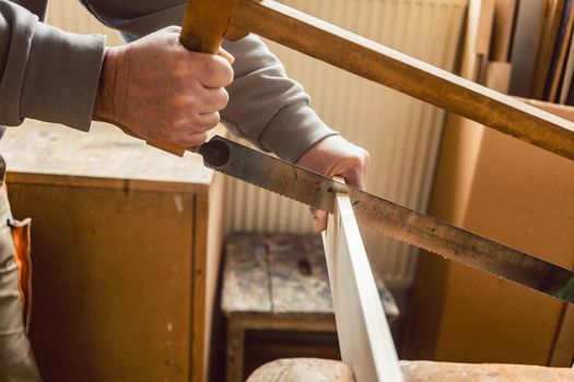 Carpenter working on wood with frame saw, close-up on his hands