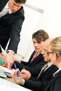 Business Team discussing documents, presumably contracts or numbers