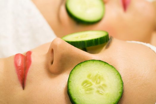 Girls in a beauty treatment with cucumber slices