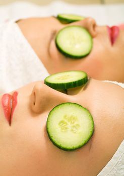 Girls in a beauty treatment with cucumber slices