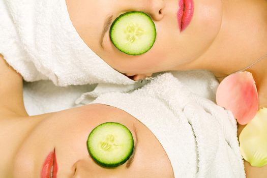 Girls in a beauty treatment with cucumber slices