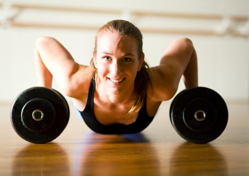 Powerful lady doing push-ups on dumbbells. training her muscles