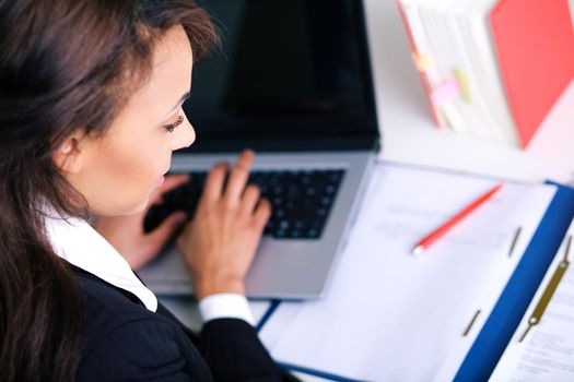 Woman working on a laptop, looking in a file