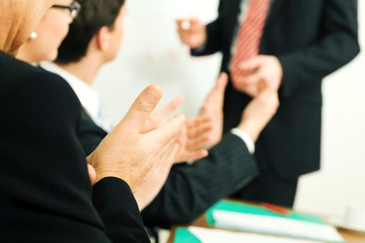 Business team applauding after a successful business presentation (selective focus only on hand in front!)