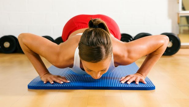 Very sportive woman doing pushups in a gym