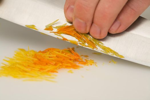 Man cutting or chopping orange and citron zests with a knife