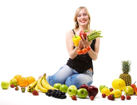 Beautiful woman sitting amidst fruits holding vegetables