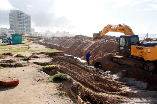 salvador, bahia / brazil - july 10, 2014: Excavator works on a work to recover the sea advance at Praça Wilson Lins, in the Pituba neighborhood in the city of Salvador.


