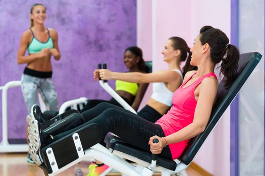 Full length side view of a fit woman laughing while listening to the instructions of a qualified fitness instructor, with sense of humor during group class for women