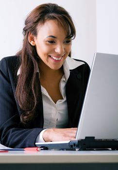 Young woman working on a laptop computer, laughing