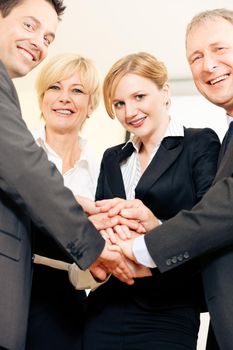 Businesspeople stacking their hands together - a strong symbol for their willingness and determination to reach a shared goal