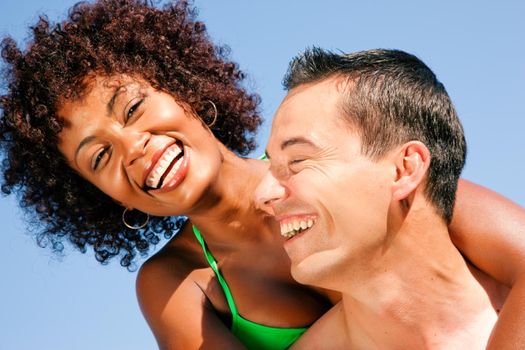 Couple in love - Woman of Brazilian origin in bikini with her man sitting under blue sky - summer and fun