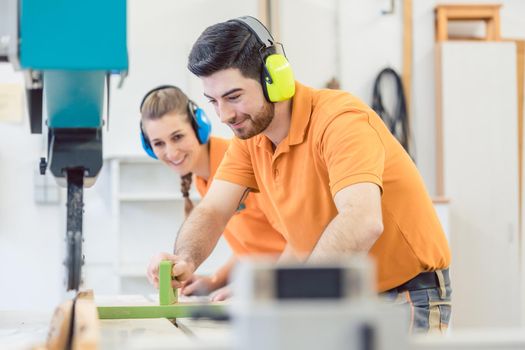 Carpenter man and woman working in workshop as a team