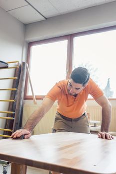 Carpenter polishing and varnishing a table in his workshop