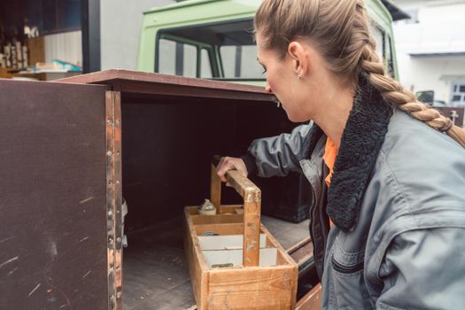 Woman carpenter loading tools in mobile workshop transporter in the morning