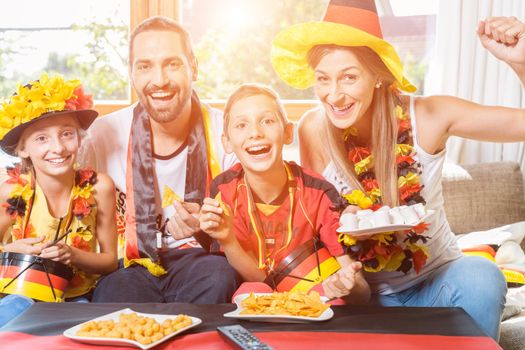 Happy family cheering for the German soccer team in front of TV