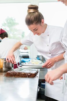 Confectioner or Patissier putting chocolate as frosting on cake