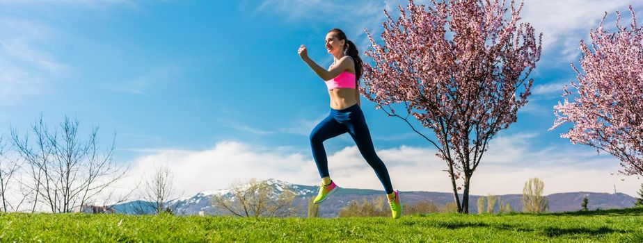 Woman sport running on hill for fitness with blossoming trees
