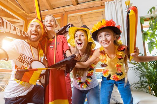 Happy family cheering for the German soccer team in front of TV