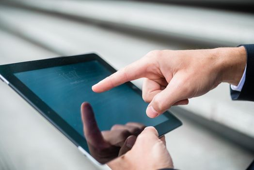 Businessman navigating on a tablet computer using his finger on the touchscreen as he surfs the internet, close up view