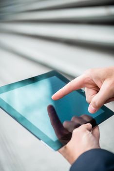 Businessman using a tablet touchscreen navigating with his finger as he browses the internet, close up on the screen