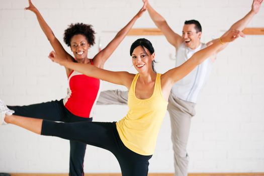 Group of three people in colorful cloths in a gym doing gymnastics