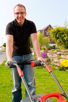 Man mowing lawn in his garden or front yard in summer