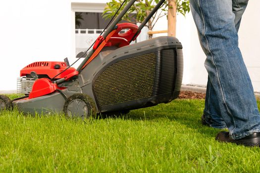 Man mowing lawn in his garden or front yard in summer