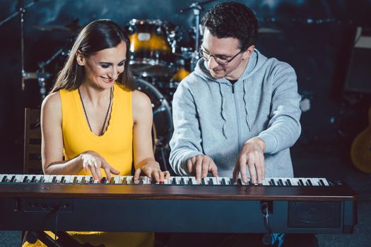 Piano teacher with his student in music school playing together