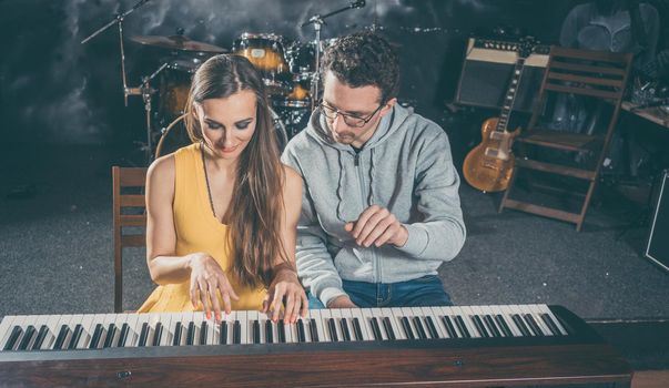 Piano teacher giving lessons to his student in music school